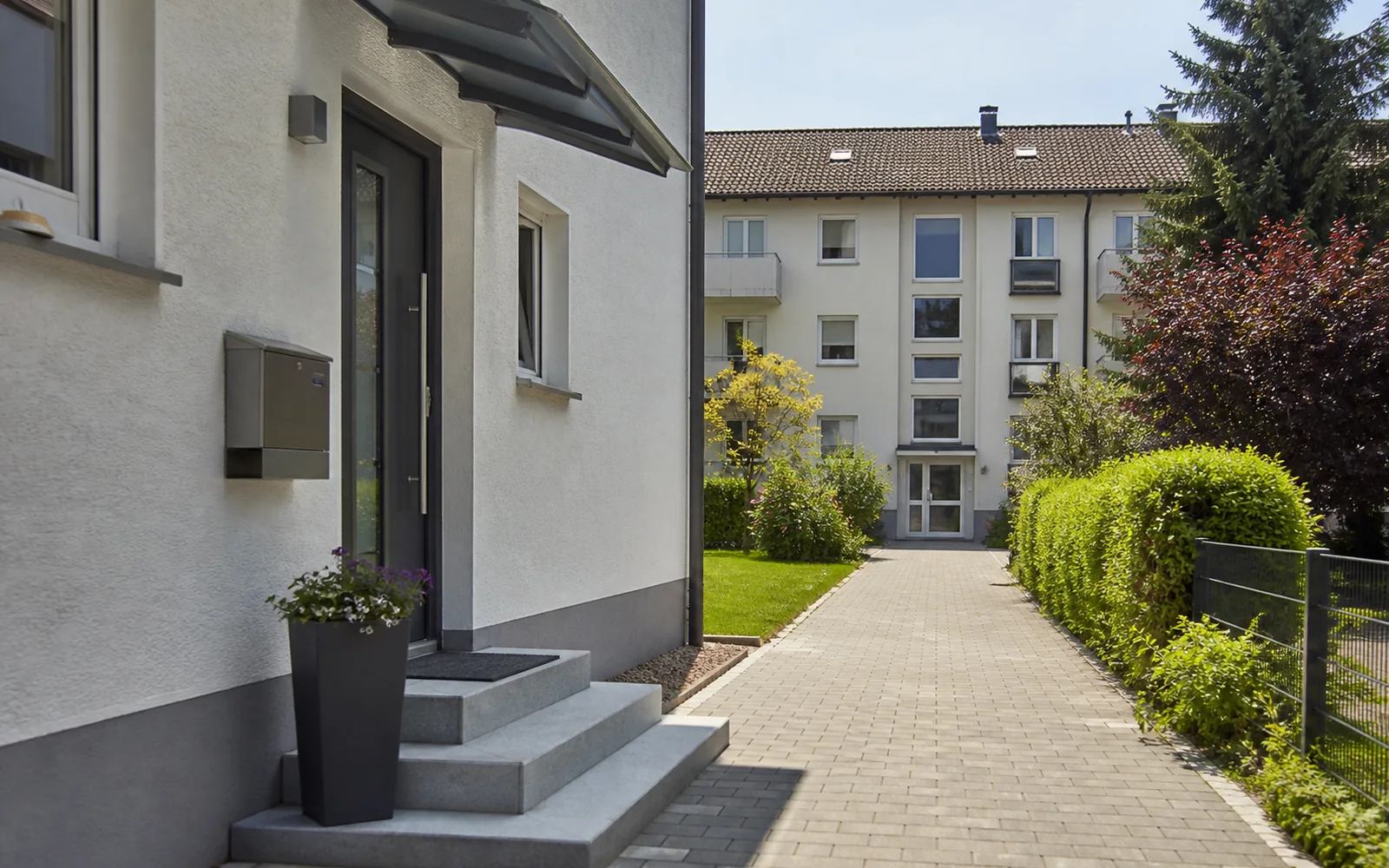 Hauseingang und Mehrparteienhaus entlang einer geraden Wohnachse